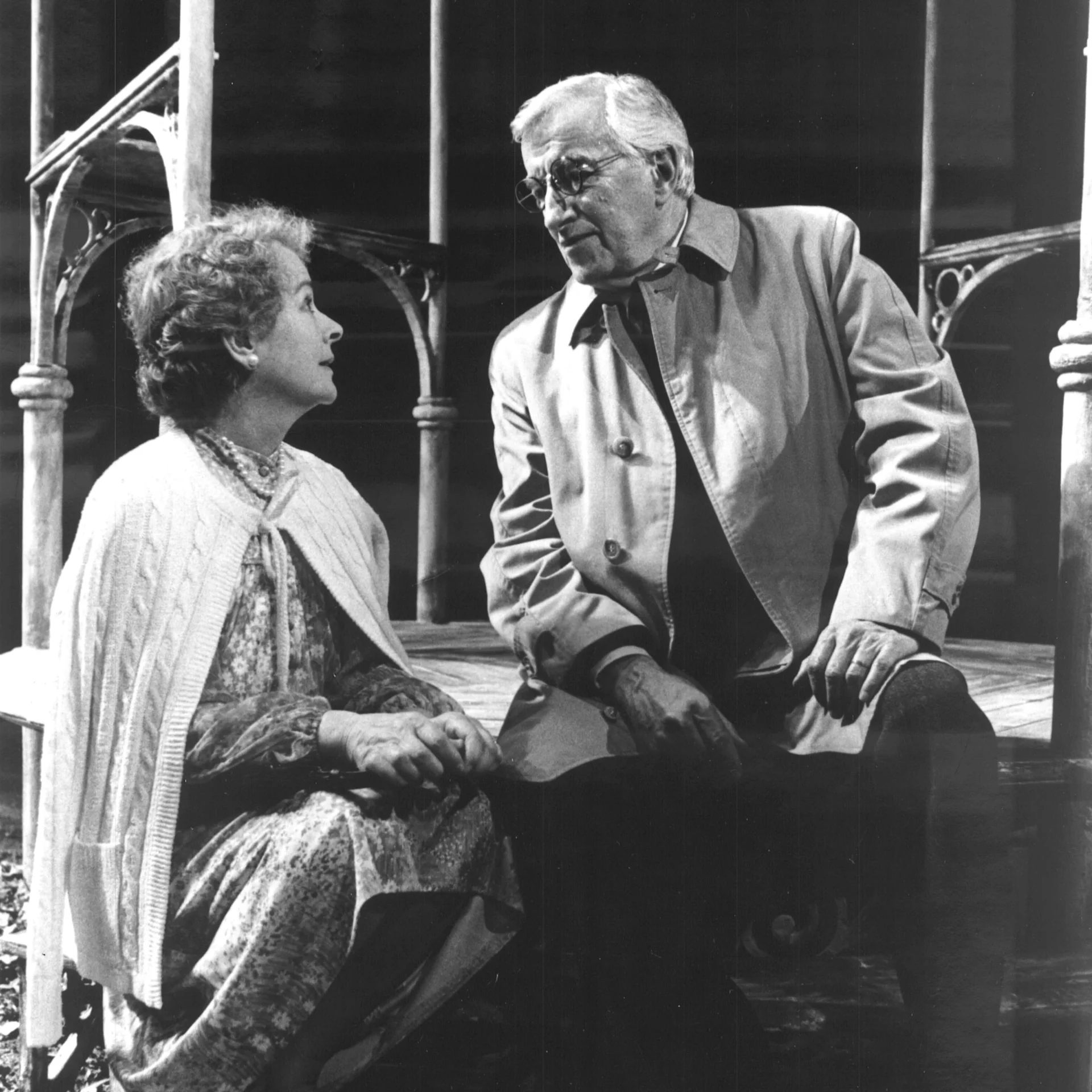 A woman and a man are seen sitting on the steps talking to each other.
